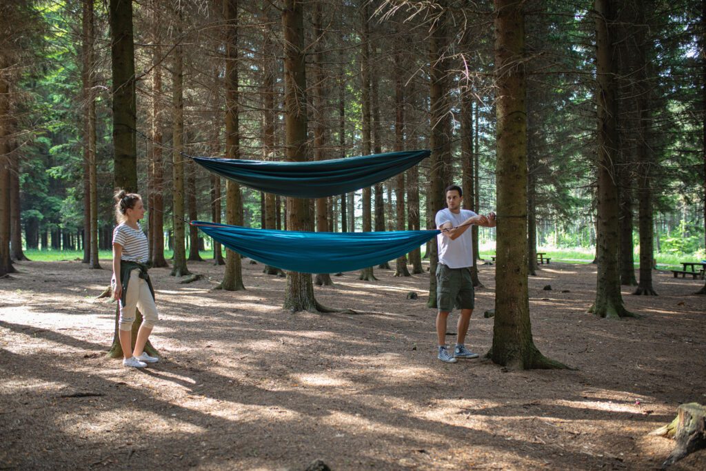 Man and girlfriend setting up hammock while out camping