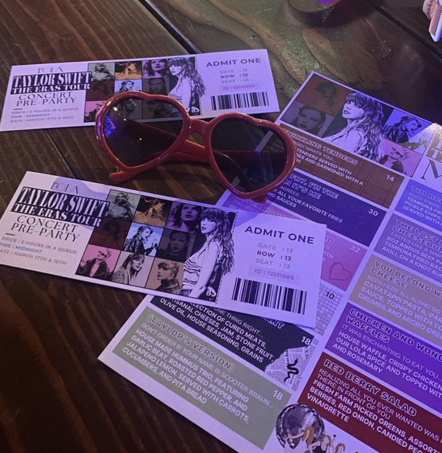 A pair of glasses sit on top of two tickets to a Taylor Swift Eras Era stadium party