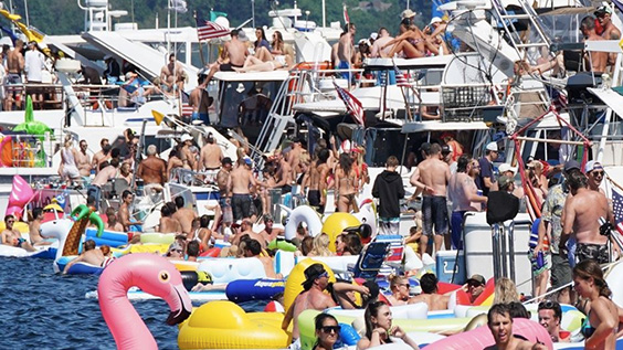 A crowd of people hang out at Seafair for the annual logboom on boats and in floaties