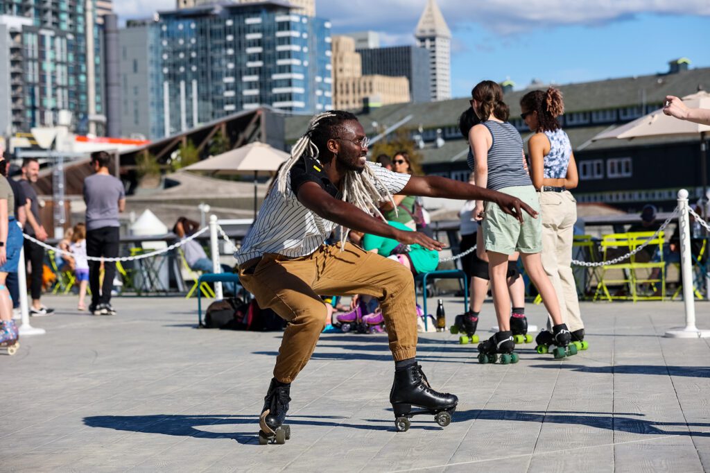 A man crouches down, smiling while roller skating on Pier 62