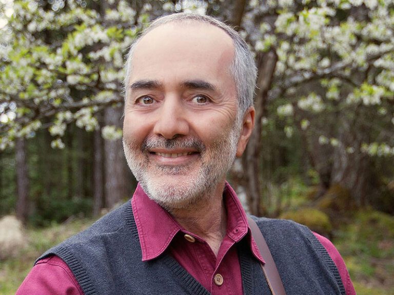 A photo of the singer Raffi in front of green trees