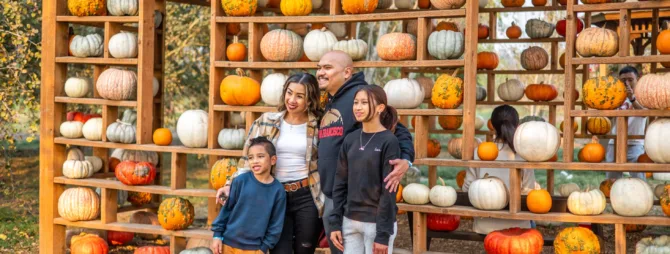 A family stands in front of a wall of pumpkins at Stocker Farms.