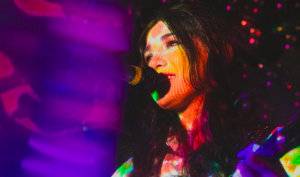 Pearl Charles performs at Freakout Festival with bright, technicolor lighting across her face.