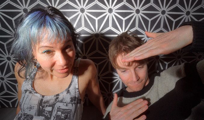 Kim and Matt pose. Kim has blue hair and Matt is covering his face with his hands.