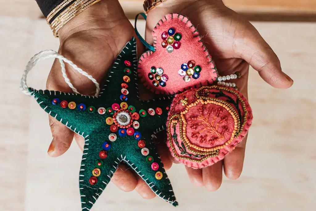An overhead shot of hands holding felt embroidered ornaments