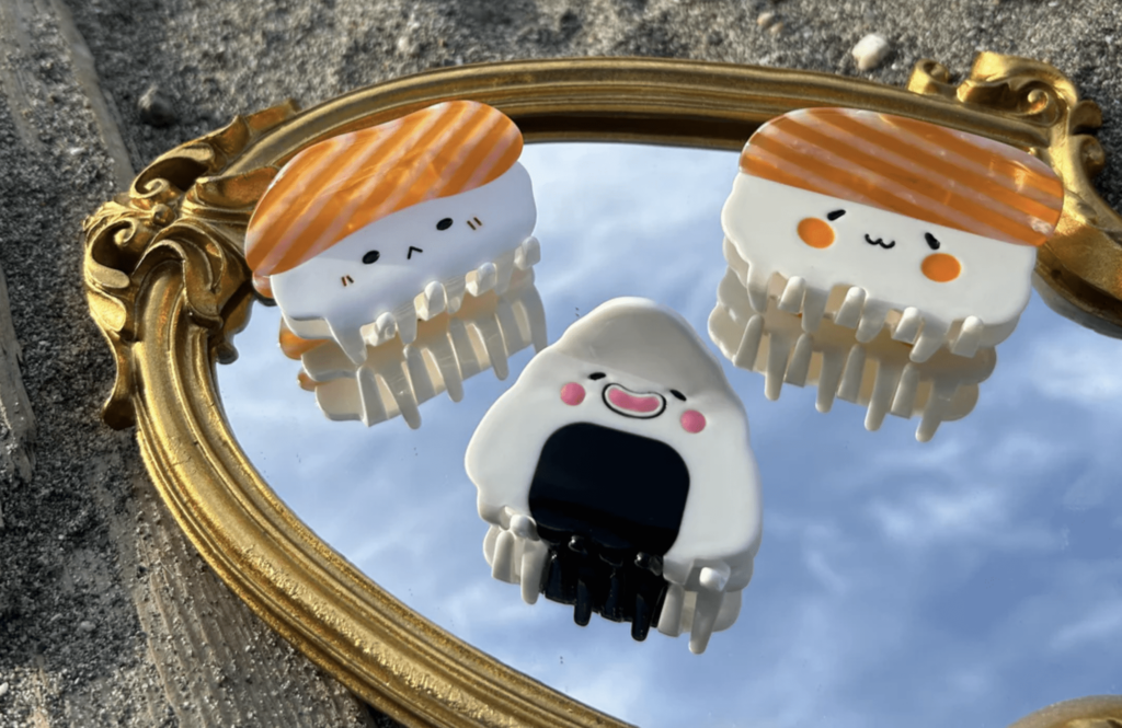 Three cute hair clips designed to look like sushi rest on gold framed mirror.
