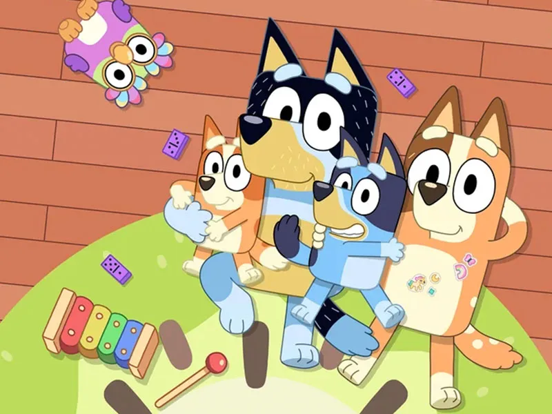 The animated character Bluey sits with his family on the floor of their home.