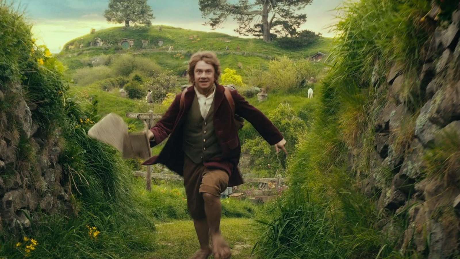 Bilbo Baggins, a young hobbit, runs through the lush green hills of the Shire in Middle-earth
