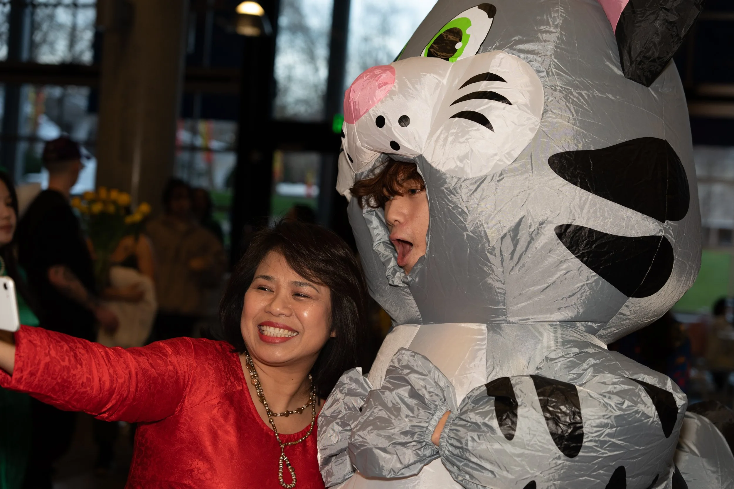 A person takes a photo with another person in an inflatable cat outfit during Year of the Cat 2023.
