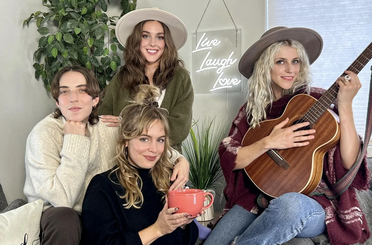 The main band members of Chastity Belt pose in front of a sign that says Live Laugh Love. They play a concert at The Crocodile in April to support their new album.