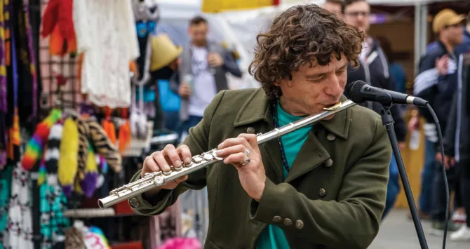 A busker plays music on a flute at the Fremont Solstice Fair.