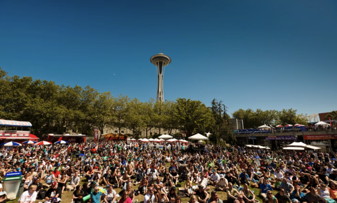 A large crowd sits on the Seattle Center's lawn during the annual Bite of Seattle food festival in Seattle, Washington.