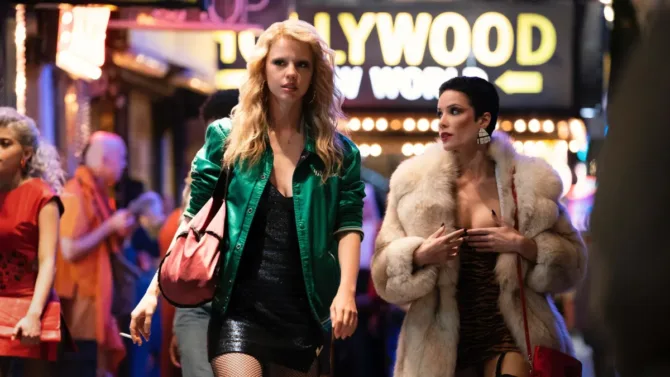 A promotional image for "MaXXXine" that shows two women walking the Hollywood strip.