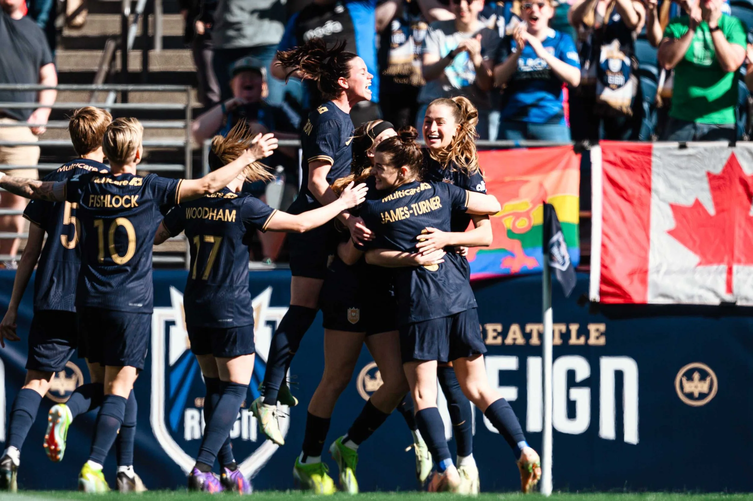 Members of the Seattle Reign crowd around each other and celebrate a goal enthusiastically.