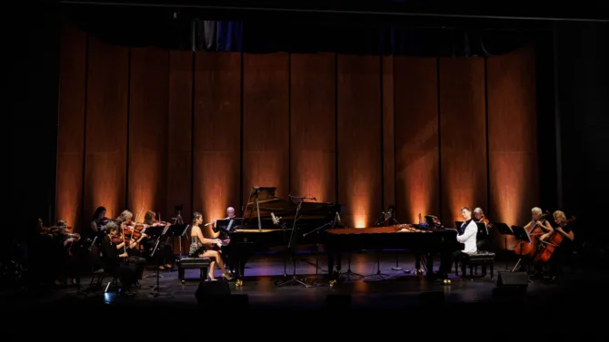 Four pianists performing on two pianos
